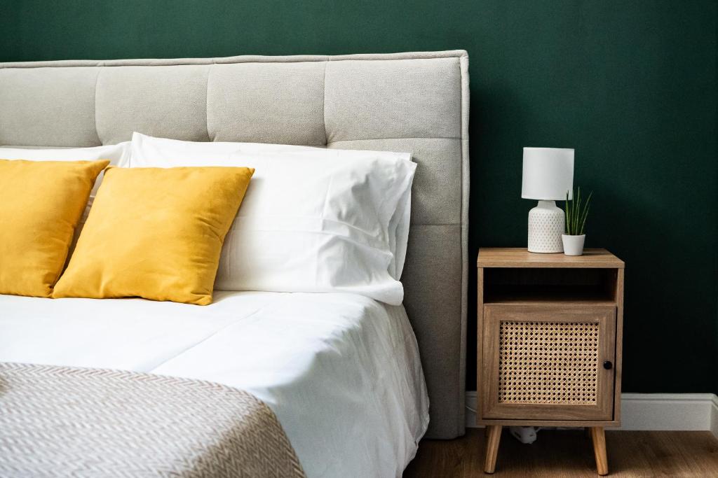 een bed met witte lakens en gele kussens naast een groene muur bij Domina Apartments Roma - San Pietro 2 in Rome