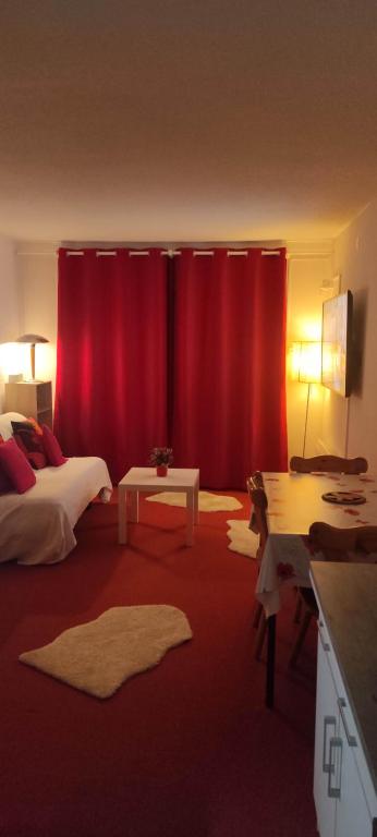 - une chambre avec des rideaux rouges, un lit et une table dans l'établissement Studio montagne 4 personnes, à Villarembert