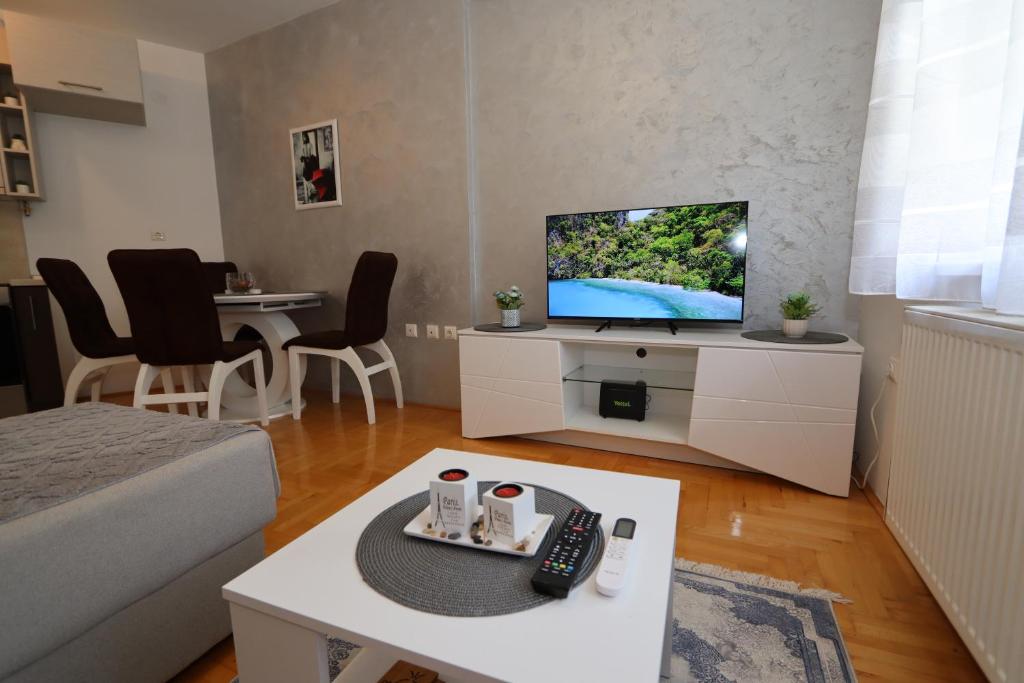 Una pequeña sala de estar con un televisor y una mesa. en Golden Royal M, en Kragujevac