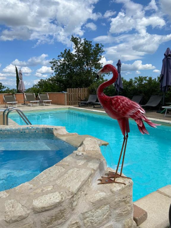 une statue d'un oiseau debout sur un rocher à côté d'une piscine dans l'établissement Apartments La Vieille Source, à Saint-Martin-dʼArdèche
