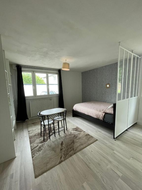 - une chambre avec un lit, une table et un lit dans l'établissement Apparemment Rennes, à Saint-Jacques-de-la-Lande