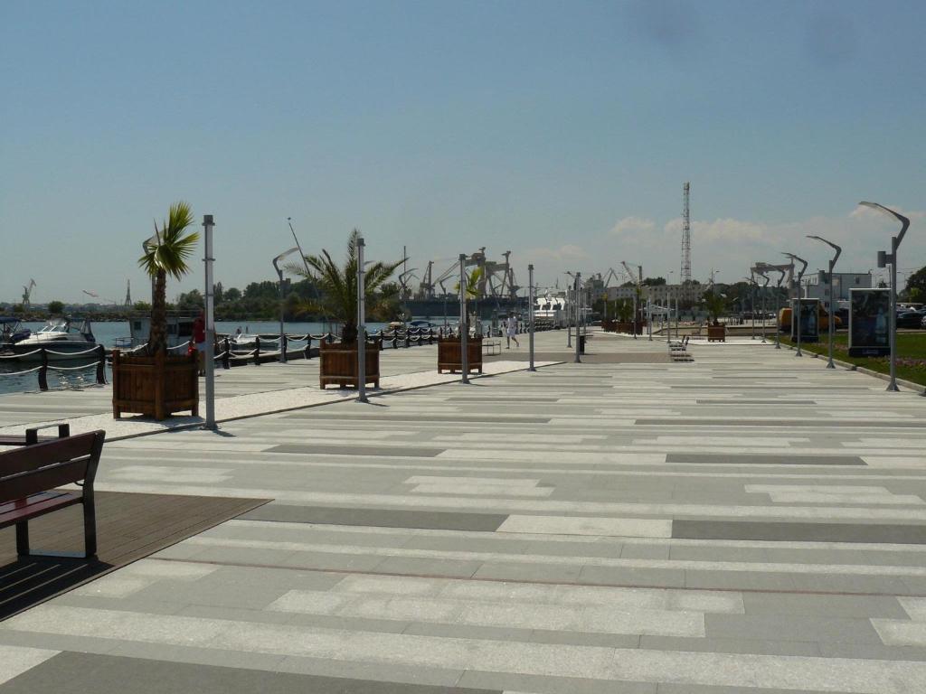 a boardwalk with benches and palm trees next to the water at Vila Rin in Mangalia