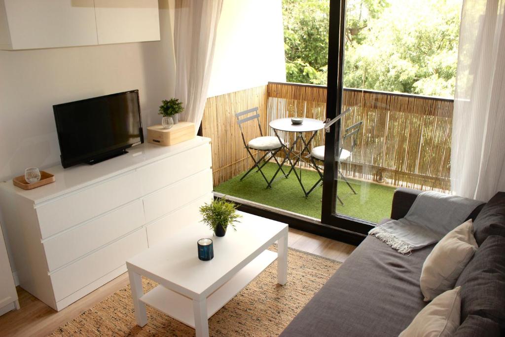 a living room with a couch and a tv and a balcony at Le Petit Moulin in Gradignan