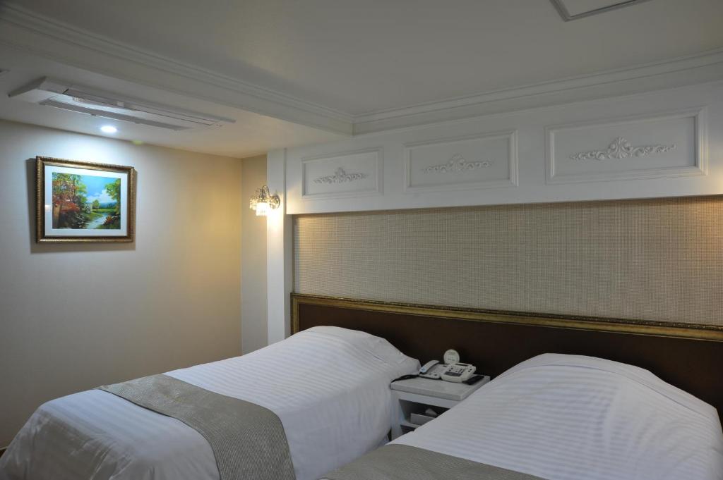 Palace Hotel Gwangju في غوانغجو: غرفة فندقية بسريرين وهاتف