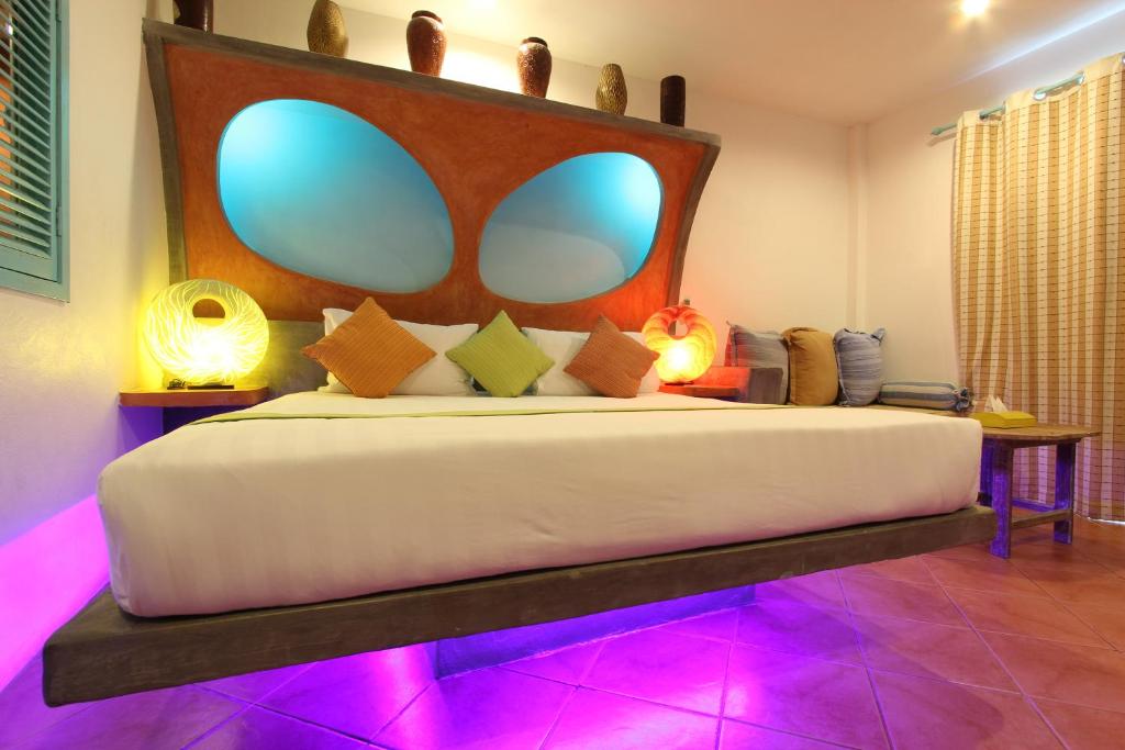 Pandora By Jida Lifestyle Hotel في شاطئ تشاوينغ: غرفة نوم مع سرير كبير مع أضواء أرجوانية