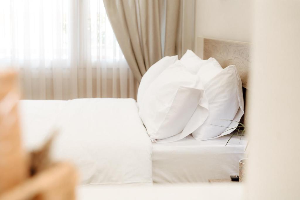 a bed with white pillows on it with a window at The Clock House in Veria