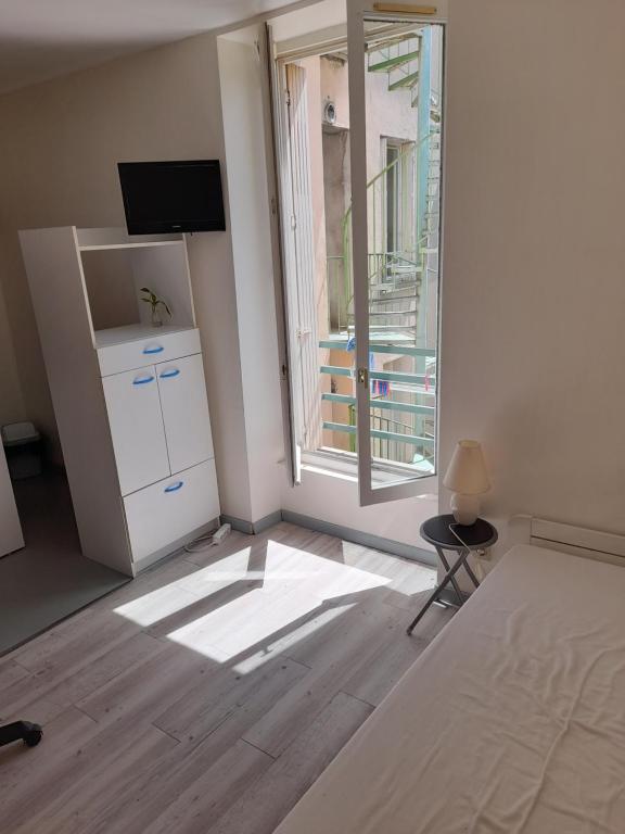 une chambre avec un lit et une grande fenêtre dans l'établissement Super appartement centre ville Digne-les-Bains, à Digne-Les-Bains