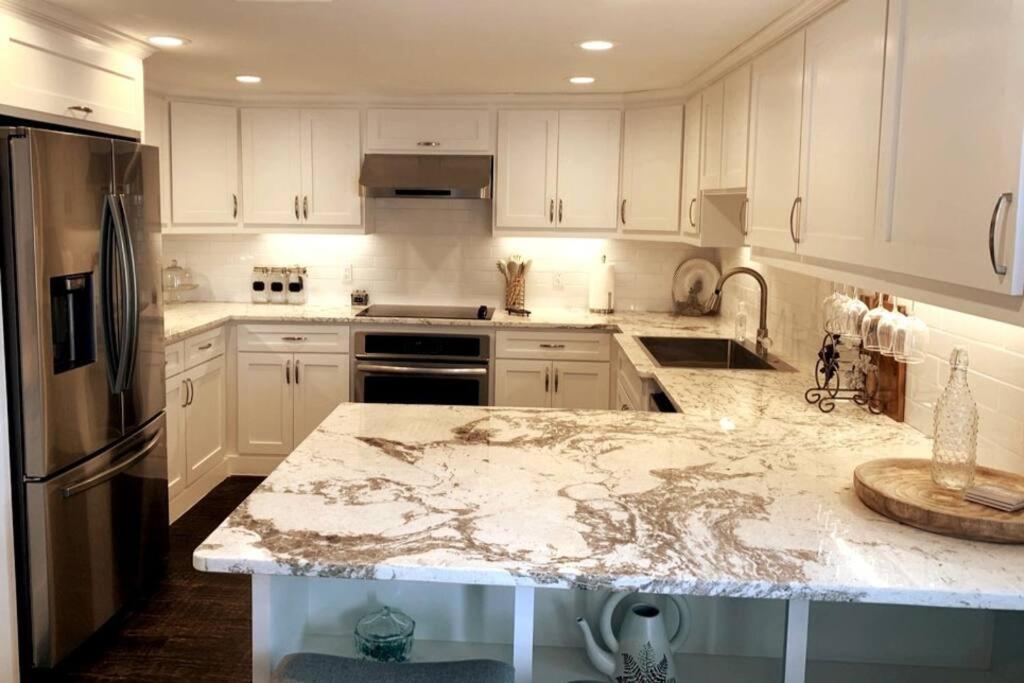 una cucina con armadi bianchi e ripiano in marmo di Blue Willow a Mead