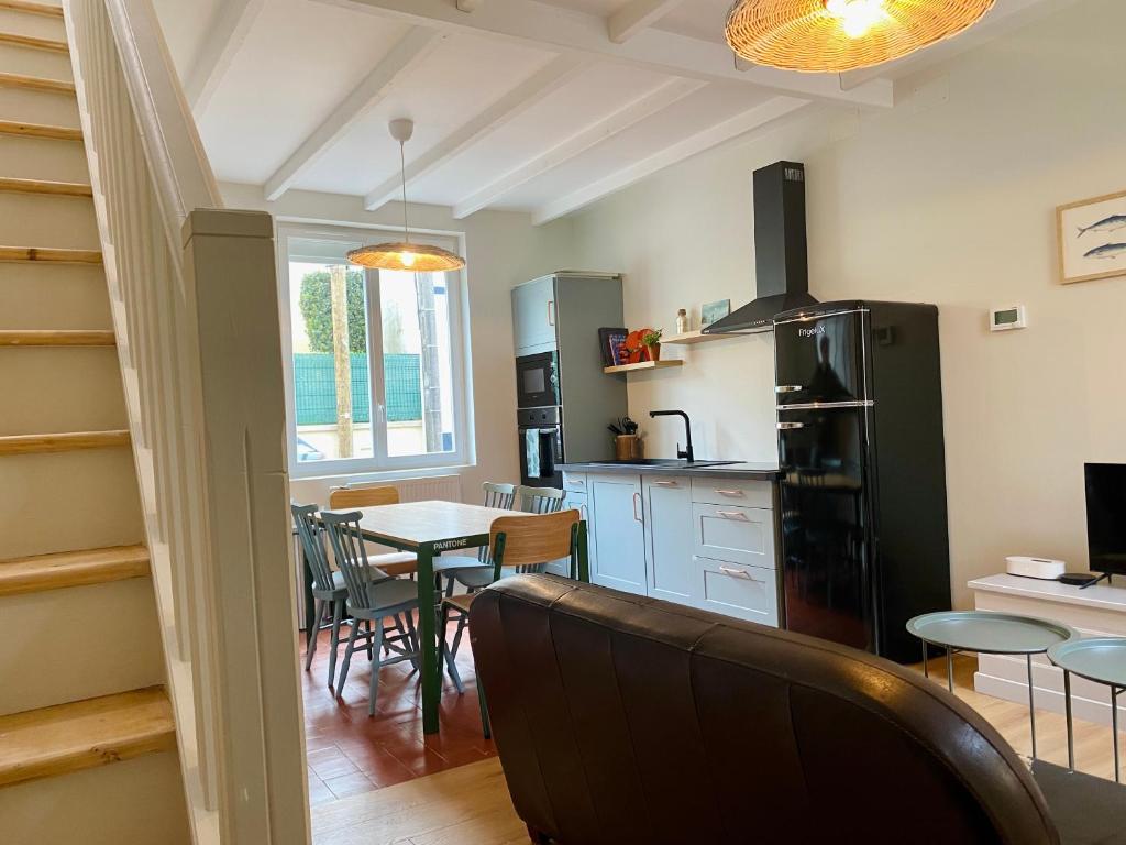 une cuisine et une salle à manger avec une table et un réfrigérateur dans l'établissement L Obione charmante maison de pêcheur rénovée proche mer avec patio extérieur, au Tréport