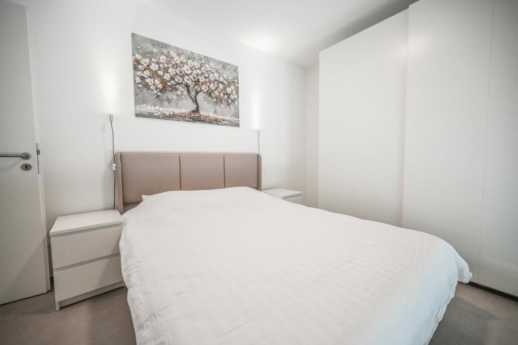 Un dormitorio con una cama blanca y un cuadro en la pared. en NEUDORF RESIDENCES, en Luxemburgo