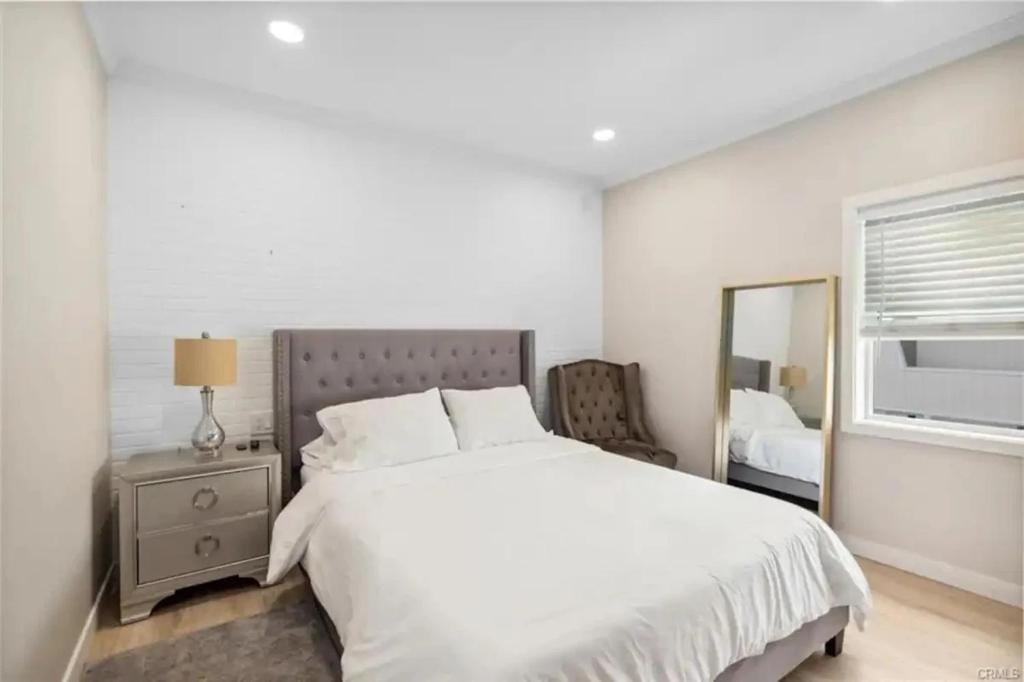 a white bedroom with a bed and a mirror at 1628 West Oceanfront Oasis - 5,8,9 in Newport Beach