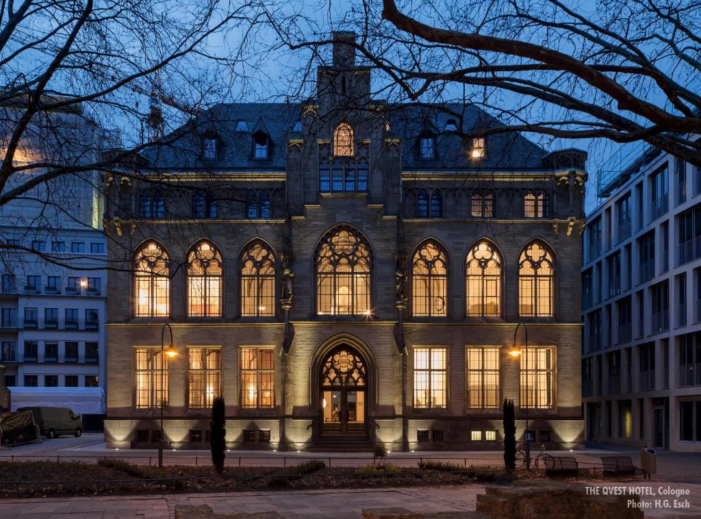 un grand bâtiment avec de nombreuses fenêtres la nuit dans l'établissement THE QVEST hideaway, à Cologne