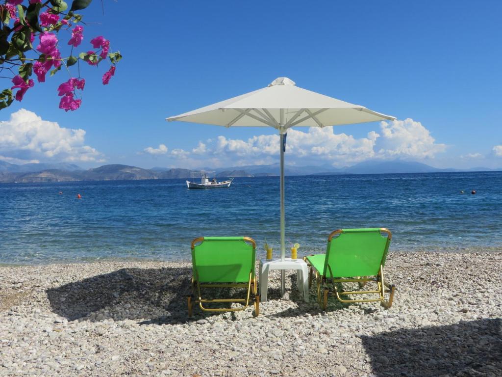 duas cadeiras e um guarda-sol numa praia em Blue Sky Studios em Xiropigado