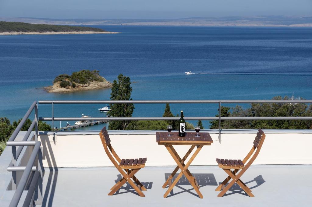 a table and two chairs on a balcony overlooking the water at Gonar 300 Rab in Supetarska Draga