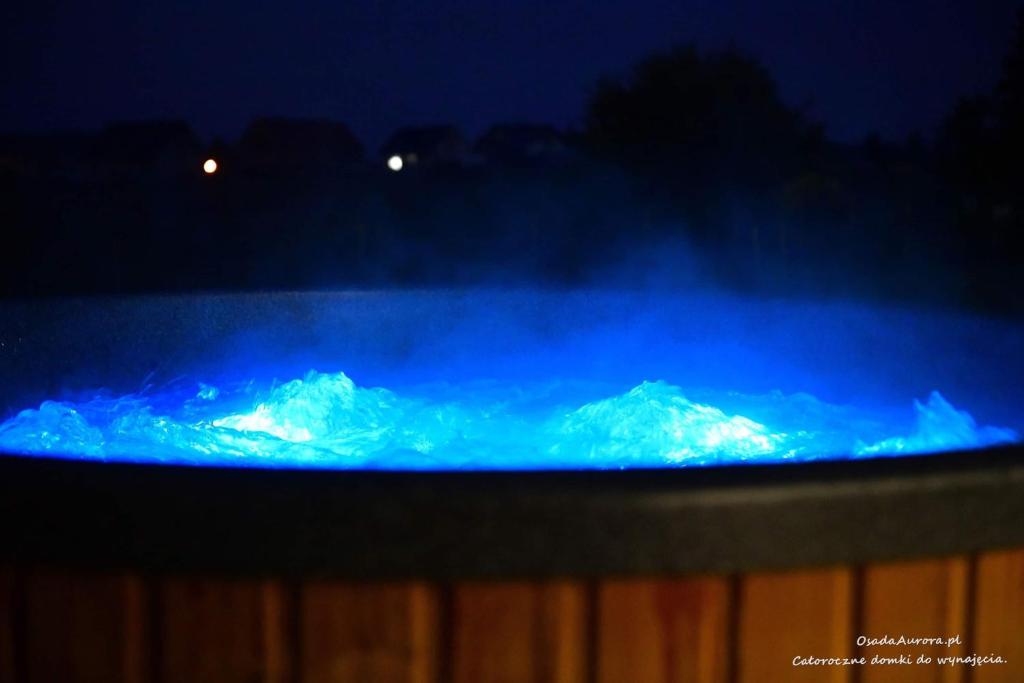 un fuego azul con montañas cubiertas de nieve en el fondo en Osada Aurora Całoroczne domki z jacuzzi z widokiem na jezioro i góry, en Miszkowice