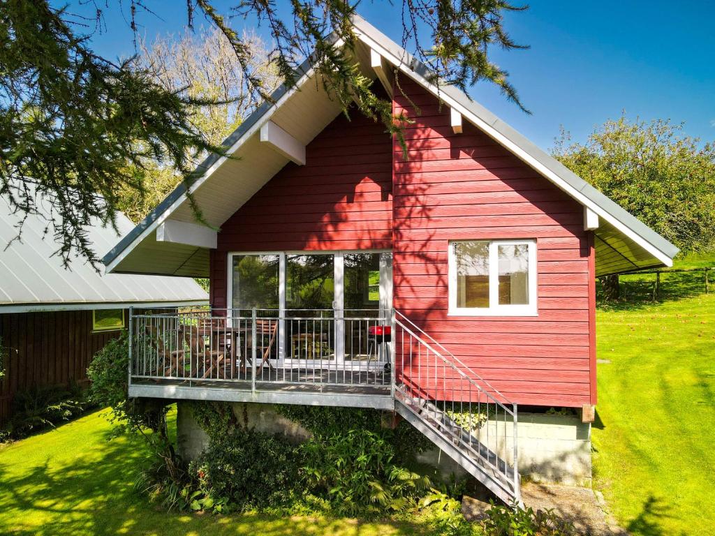 ein rotes Haus mit einer Veranda und einem Balkon in der Unterkunft Ta Mill Cottages & Lodges - Meadowview Chalet 2 in Launceston