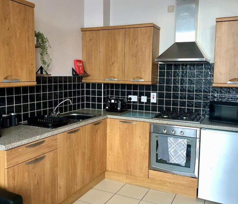a kitchen with wooden cabinets and a stove at Cliftonville Apartments in Belfast