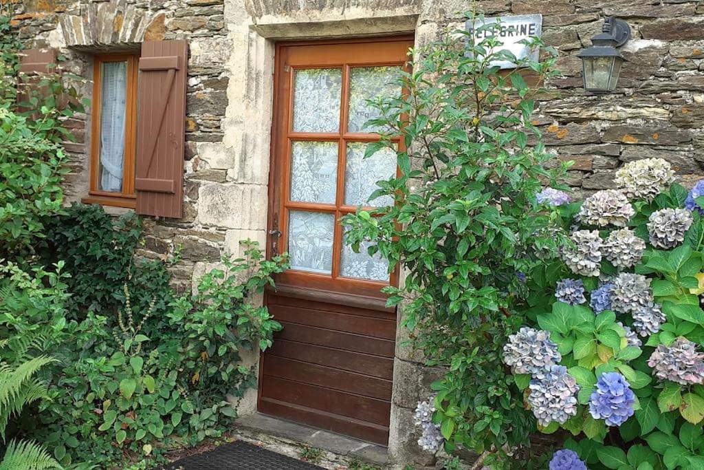 - un bâtiment en pierre avec une porte et des fleurs dans l'établissement Pélégrine, à Gabriac