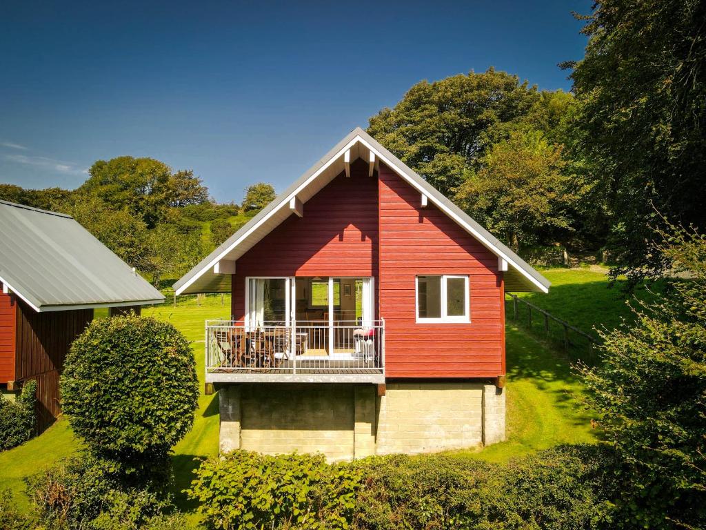 ein rotes Haus mit einem Balkon im Hof in der Unterkunft Ta Mill Cottages & Lodges - Meadowview Chalet 4 in Launceston