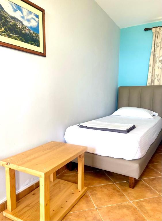 a small bedroom with a bed and a wooden table at Chalet Ambel in Dhërmi