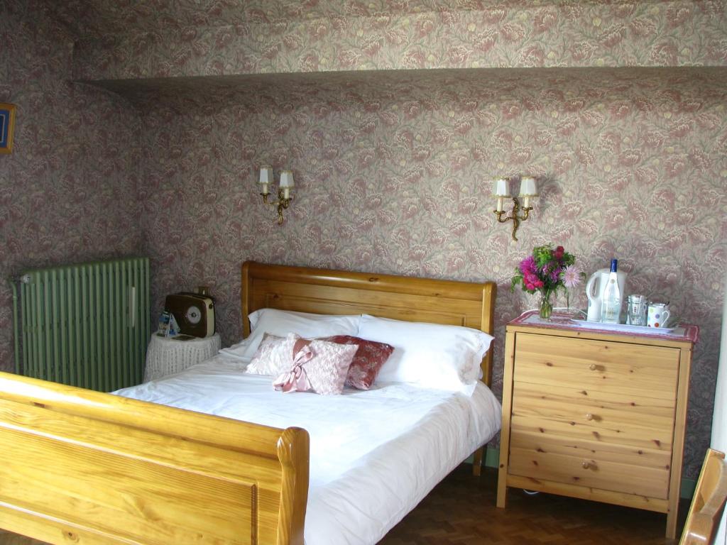 a bedroom with a bed and a dresser and flowers at Chambre d'hôtes des Monédières in Treignac