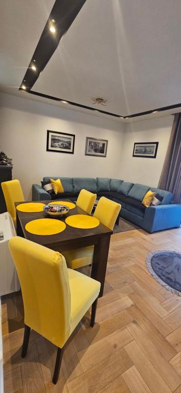 Una sala de estar con una mesa y sillas amarillas. en Apartment M, en Trebinje