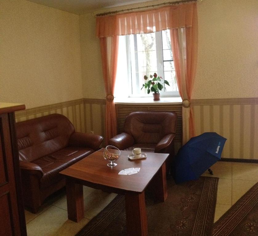 sala de estar con 2 sillas, mesa y ventana en Grad Hotel, en Cherepovets