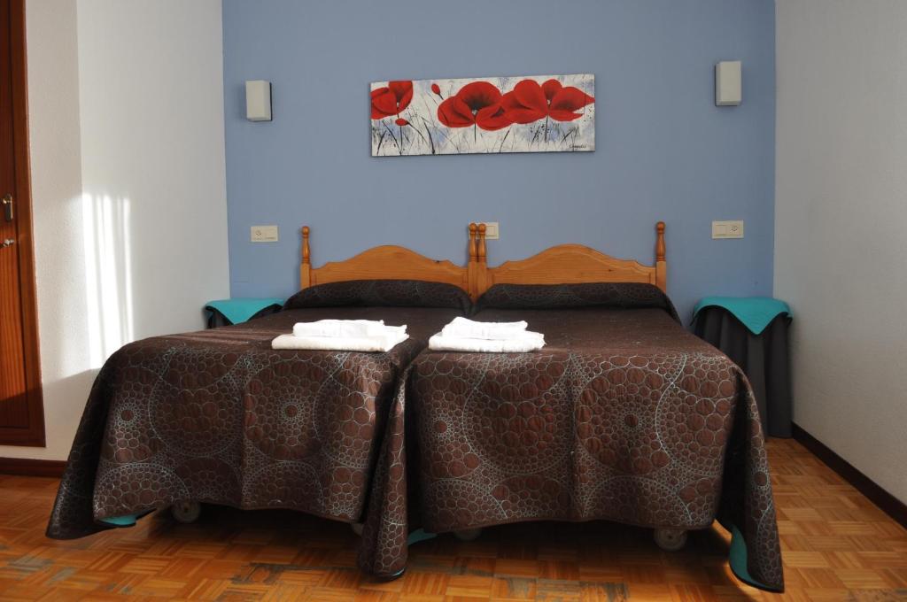 Hostal La Tablada في نافالينو: غرفة نوم عليها سرير ووسادتين