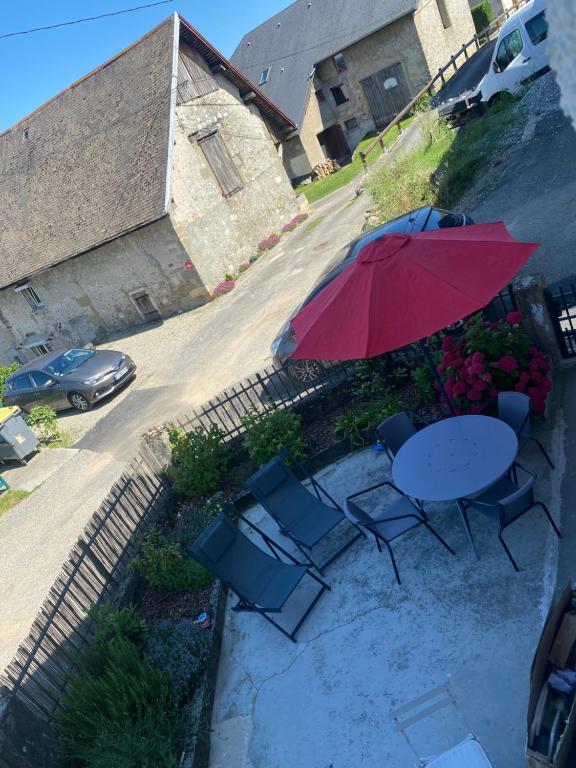 une table et des chaises avec un parapluie rouge et une voiture dans l'établissement Maison de village entre lac et montagne, à La Motte-Servolex