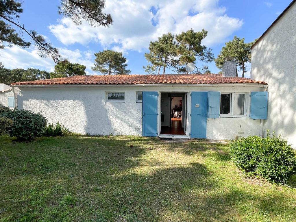 une maison blanche avec des portes bleues et une cour dans l'établissement Villa 4 pièces à La Palmyre, proche mer et commerces, patio, barbecue, animaux admis, parking inclus - FR-1-705-40, aux Mathes