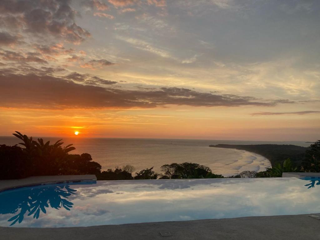 乌维塔Ballena Paraíso Lodge的海洋上的日落,带游泳池