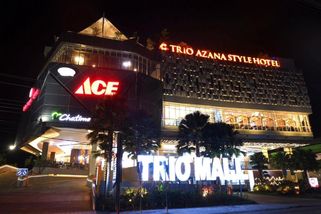 a hotel with a neon sign in front of it at Trio Azana Style Kebumen in Kebumen