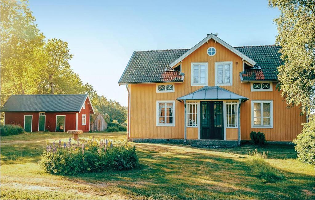 una casa arancione con un fienile rosso in un cortile di Three-Bedroom Holiday Home In Sodra Vi a Södra Vi