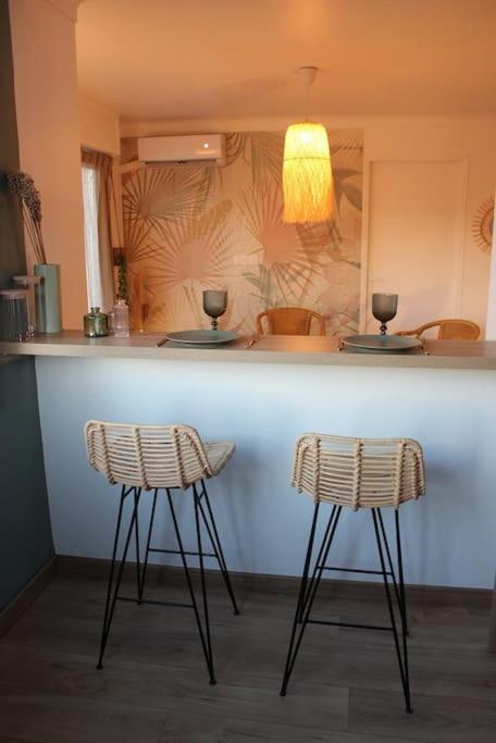 deux tabourets de bar assis à un comptoir dans une cuisine dans l'établissement Joli 2 pièces tendance 5 mns de la plage, à Torcy