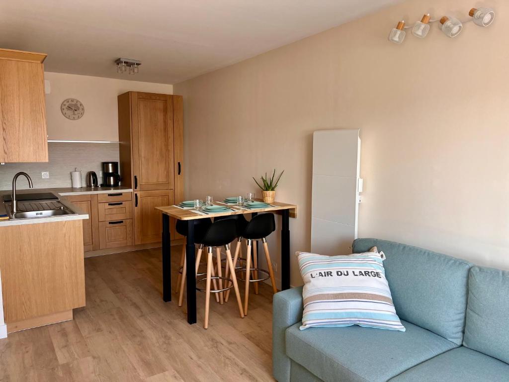 un salon avec un canapé bleu et une cuisine dans l'établissement Appartement bord de mer Houlgate, à Houlgate