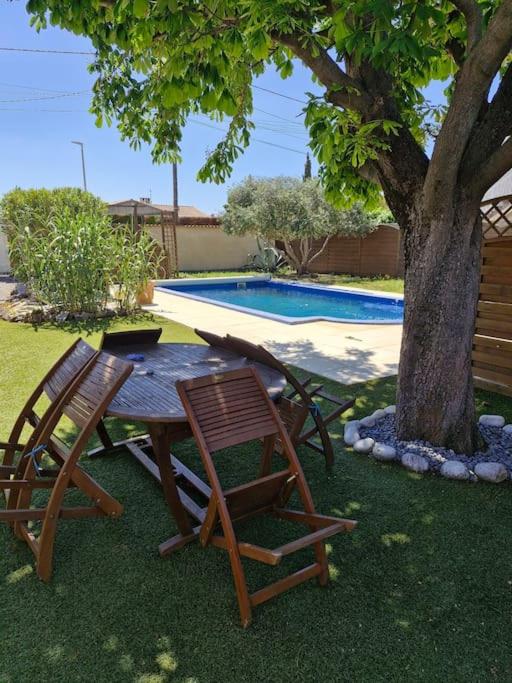 une table et deux chaises assises à côté d'un arbre dans l'établissement Charmante maison de vacances, à Lézignan-Corbières
