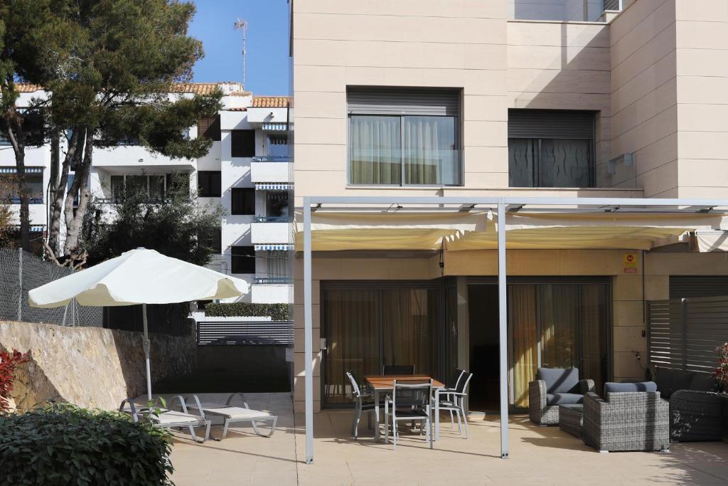 een patio met een parasol en een tafel en stoelen bij AT014 A pocos metros de la playa, equipamiento completo, piscina comunitaria in Torredembarra