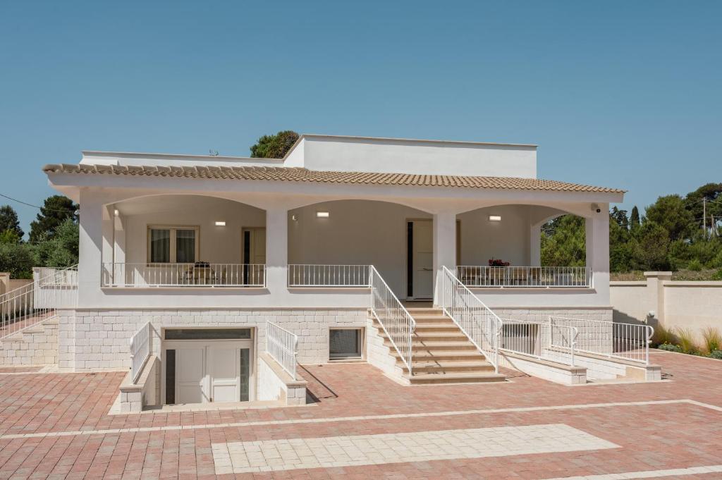a large white house with a staircase in front at Casa Vacanze Villa MaeMi in Maruggio