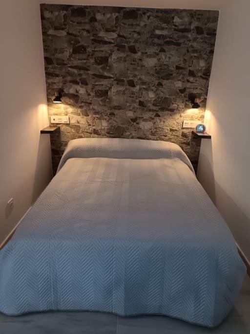 a white bed in a room with a brick wall at Casa El Papamoscas in Burgos