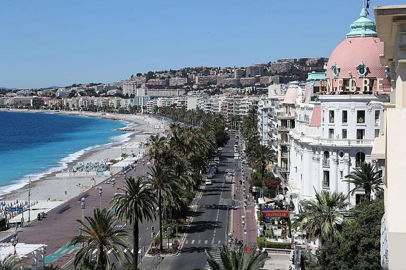 - une vue sur une plage bordée de palmiers et de bâtiments dans l'établissement AG 4 Calif 4 galaxie, à Nice