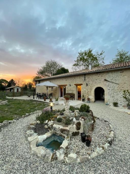 a stone house with a pond in the yard at Gite spacieux - 3 chambres - Calme et charmant in Cubnezais