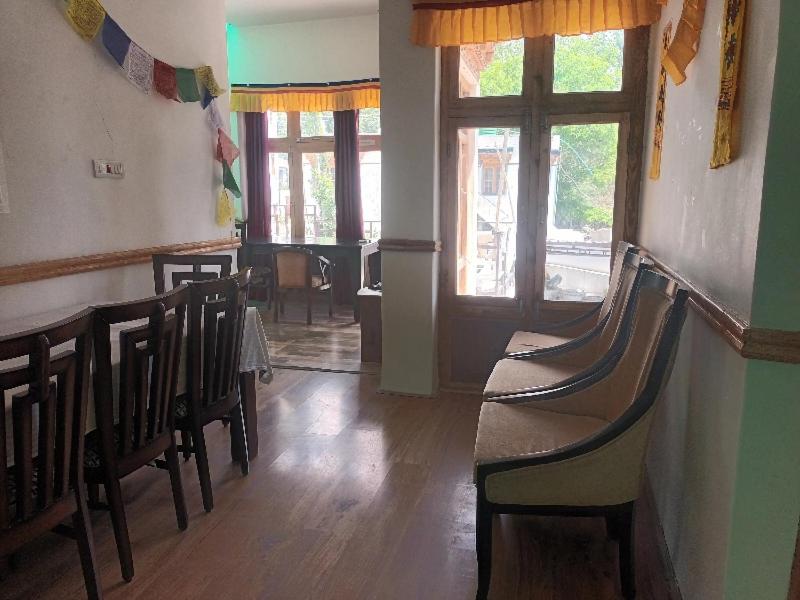 Un comedor con sillas y mesa y ventanas. en Skara Homes, en Leh