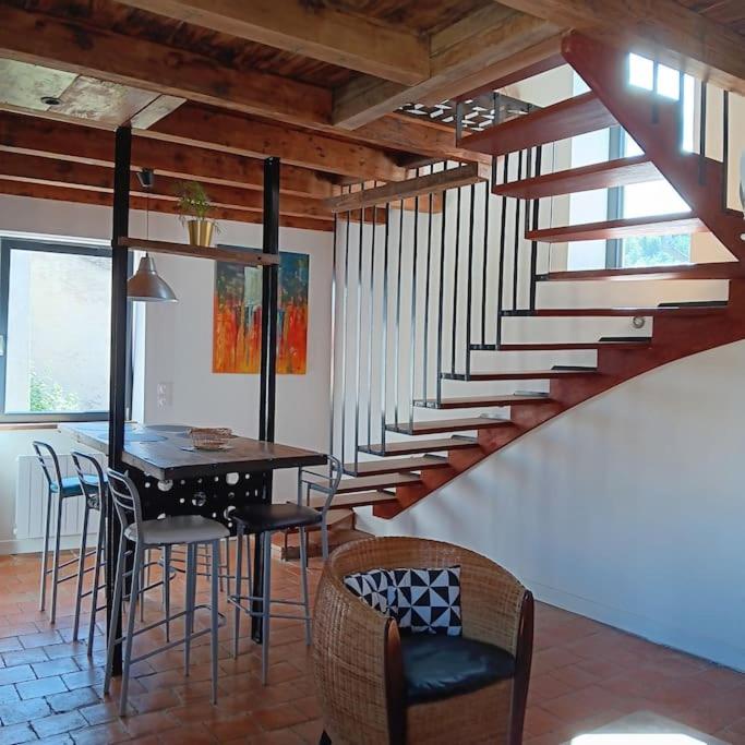 une salle à manger avec une table et des chaises et un escalier dans l'établissement Maison d'artistes avec cour au cœur du vignoble, à Saint-Gengoux-de-Scissé