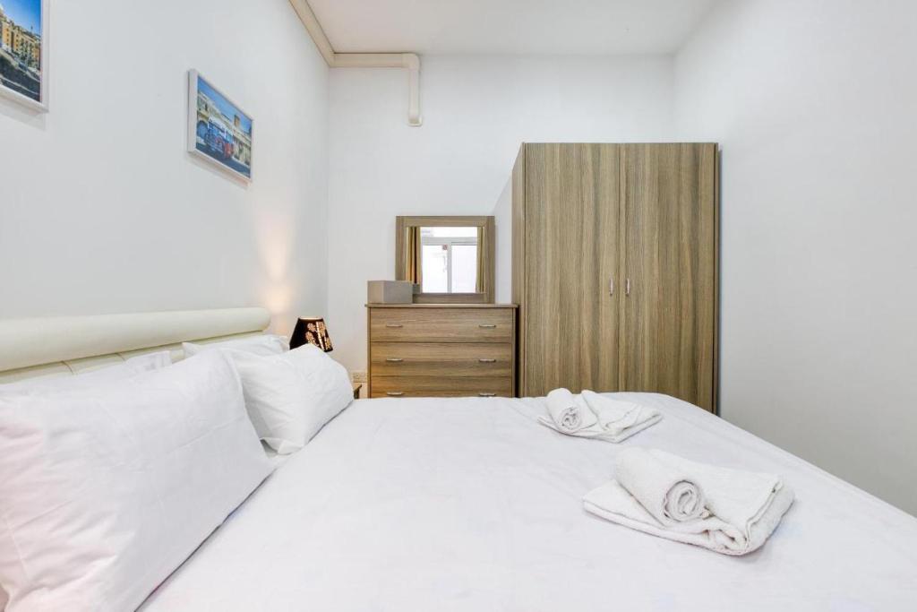 a bedroom with a white bed with towels on it at NR Retreat in Il-Gżira