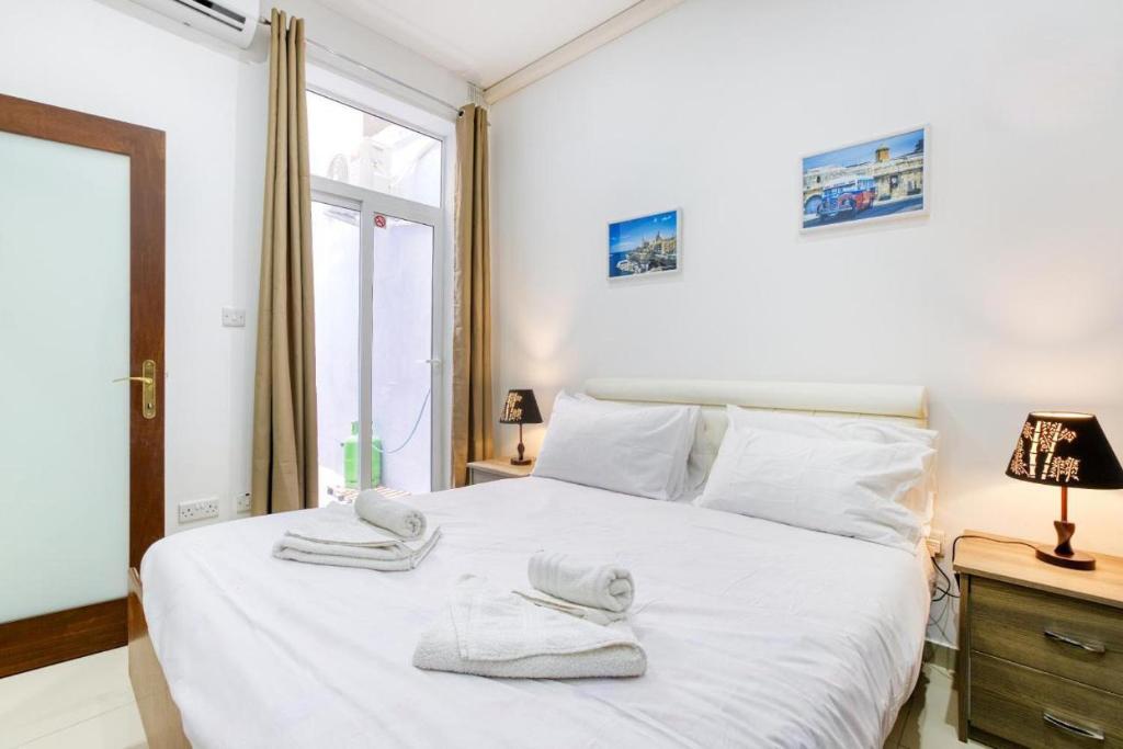 a bedroom with a white bed with towels on it at NR Retreat in Il-Gżira
