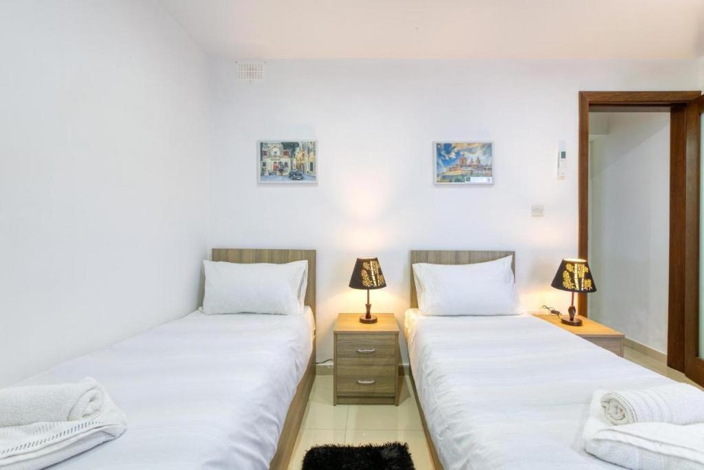 two beds in a room with two lamps at NR Retreat in Il-Gżira