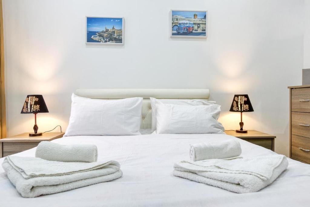 a bedroom with a white bed with towels on it at NR Retreat in Il-Gżira