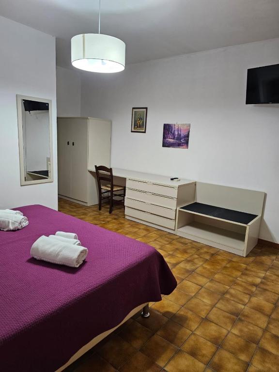 a bedroom with a purple bed and a desk at Hotel Fernanda in Letojanni