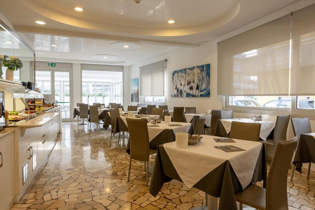 a restaurant with tables and chairs in a room at Hotel Bristol in Caorle