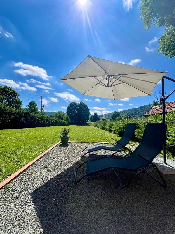 a chair and an umbrella next to a field at Spacious Montain House with Amenities, close to the Seaside in Mrkopalj